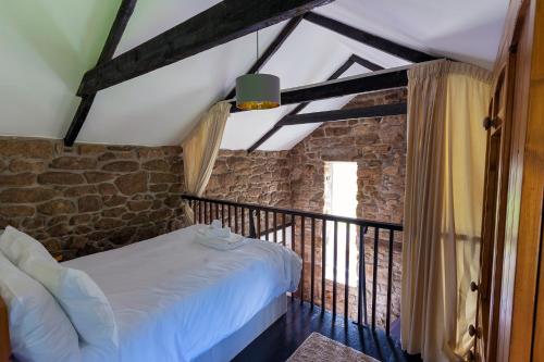 1 dormitorio con cama y pared de piedra en Beautiful Cornish barn in the stunning Lamorna valley with large garden en Paul