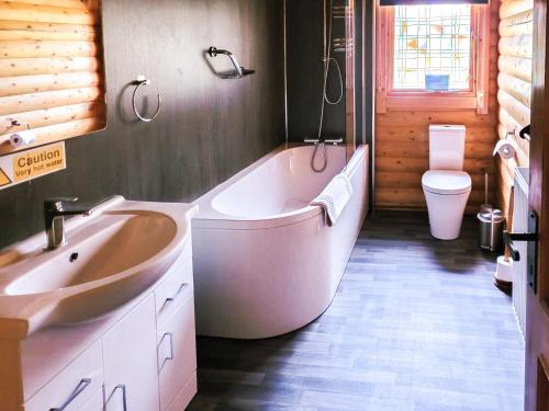 a bathroom with a tub and a sink and a toilet at Ardle Lodge in Enochdhu