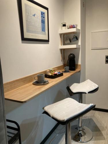 a counter with two stools in a room at AUX 4 LOGIS Appart-hotel - Studio Le Roof - Une vue splendide - Petit déjeuner inclus 1ère nuit in Foix