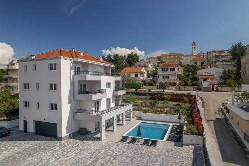 a white building with a swimming pool next to a building at Villa Barbara & Zoran with heated swimming pool in Seget Vranjica