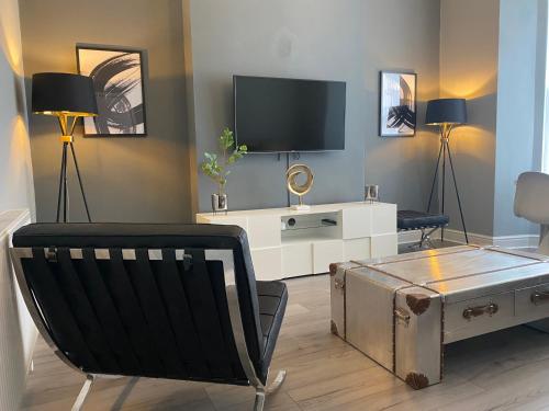 a living room with a tv and a chair and a table at Aspen House - Apartment 1 in Colwyn Bay