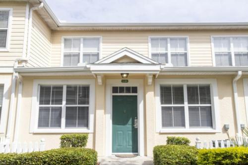 una casa con una puerta verde y ventanas en Charming 3-Bedroom Villa in Gated Community - Your Perfect Getaway! en Kissimmee