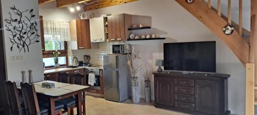 a kitchen with a refrigerator and a table and a television at DOMEK-NADMORSKI ZAKĄTEK in Pogorzelica