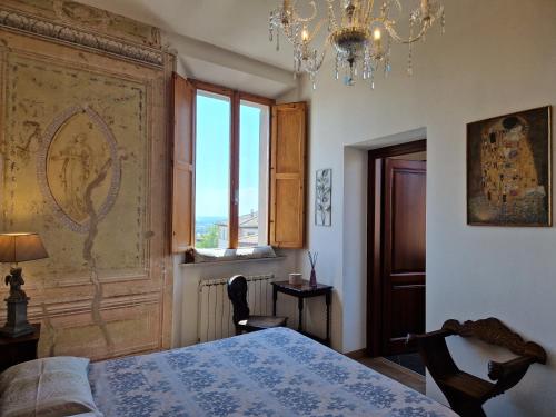 a bedroom with a bed and a chandelier and a window at “Attico Garibaldi” nel cuore della Toscana in Sinalunga