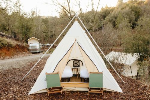 a white tent with a bed in it on the side of a road at AutoCamp Yosemite in Midpines