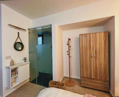 a bedroom with a shower and a wooden cabinet at Havana Zimmer צימר הוואנה in Majdal Shams