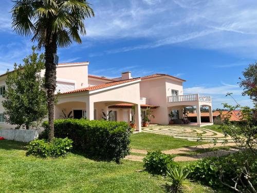 a large house with a palm tree in the yard at Casa do Cuco in Esposende