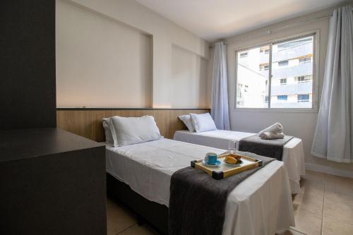 ein Hotelzimmer mit 2 Betten und einem Fenster in der Unterkunft STH52 - Quadra Mar, 4 Dorm, Centro, Climatizado in Balneário Camboriú