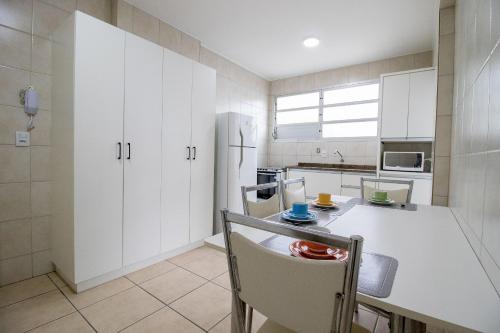 eine Küche mit weißen Schränken und einem weißen Kühlschrank in der Unterkunft STH52 - Quadra Mar, 4 Dorm, Centro, Climatizado in Balneário Camboriú