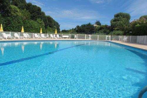 une grande piscine bleue avec des chaises et des arbres dans l'établissement LA BADINE Appartement for 4 By Sunset, à Antibes