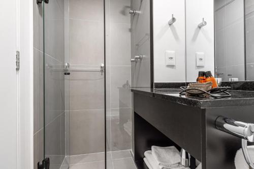 uma casa de banho com uma cabina de duche em vidro e um lavatório. em 360 Vita Bom Retiro em São Paulo