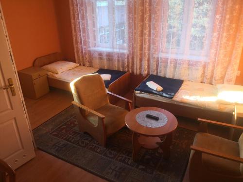 Habitación con 2 camas, silla y mesa. en Ośrodek Wypoczynkowy Janówka, en Ciechocinek