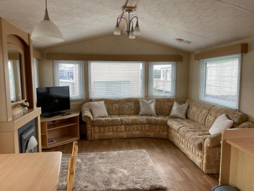 a living room with a couch and a tv at MV194 Golden Palm Resort in Chapel Saint Leonards