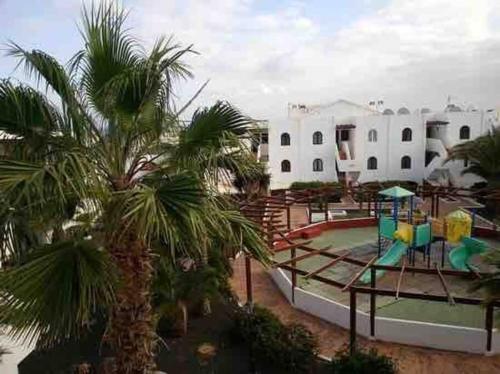 a playground in front of a building with palm trees at Apartamento Casa Carmen Teguisol in Costa Teguise