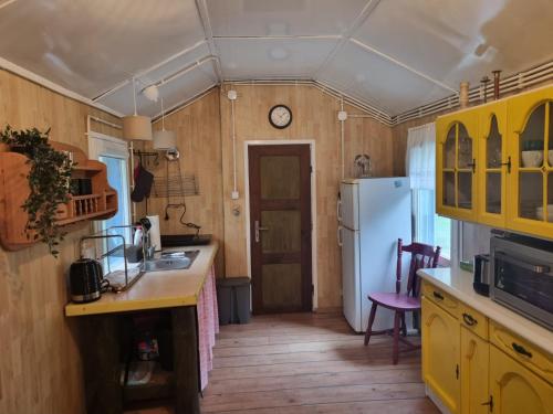 uma cozinha com armários amarelos e um frigorífico branco em Dom Pod Brzozami Lipinki Bory Tucholskie - psy, koty mile widziane! em Lipinki