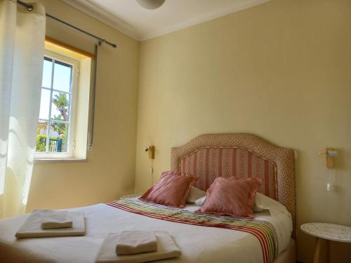 カザル・ダ・ラゴア・セッカにあるPraia Del Rey Vila Piscinaのベッドルーム1室(ピンクの枕2つ、ベッド1台付)