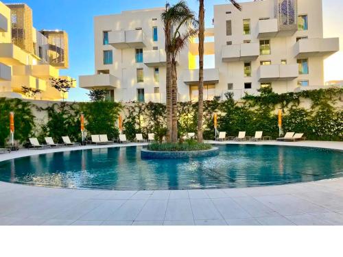 a swimming pool with chairs and a palm tree in front of a building at Duplex Rooftop d'exception terrasse panoramique de 100 m2 in Casablanca