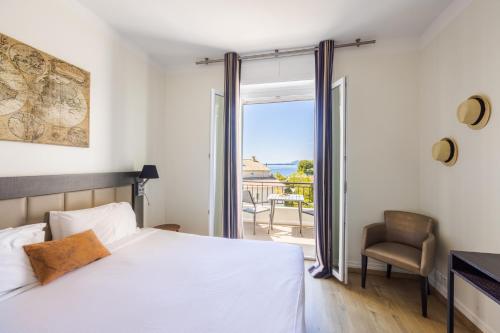 a bedroom with a bed and a sliding glass door at Hôtel La Villa Cap d’Antibes in Juan-les-Pins