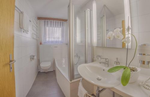 a white bathroom with a sink and a toilet at Apartments Bergrose in Saas-Fee