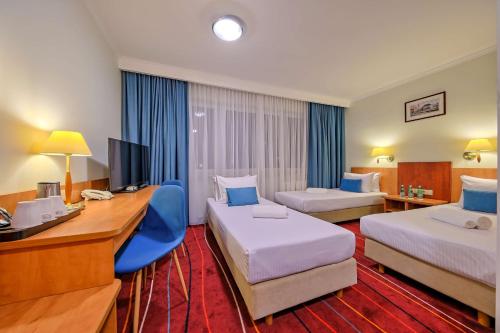 a hotel room with two beds and a desk at Best Western Hotel Portos in Warsaw