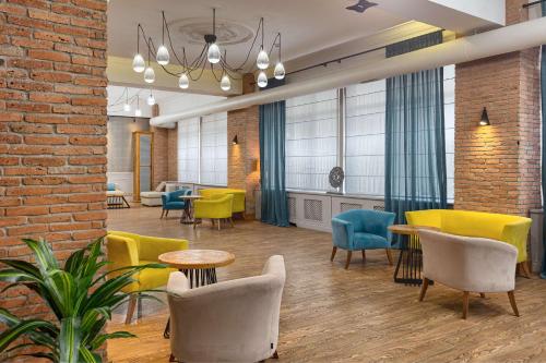 a lobby with chairs and tables and a brick wall at Best Western Tbilisi Art Hotel in Tbilisi City