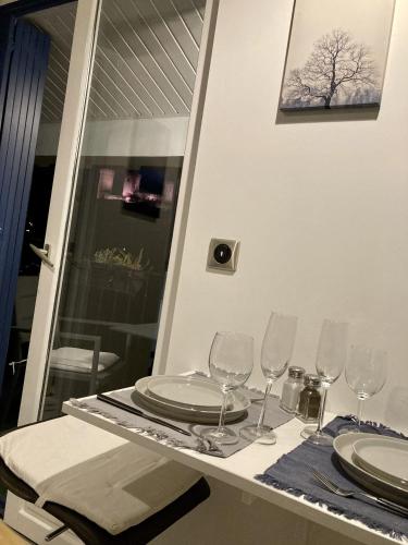 a table with plates and wine glasses on it at AUX 4 LOGIS Appart-hotel - Studio Le Roof - Une vue splendide - Petit déjeuner inclus 1ère nuit in Foix