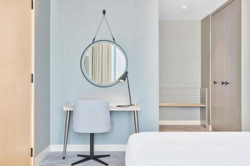 a bedroom with a mirror and a desk with a chair at Radisson Blu Hotel Riyadh Convention and Exhibition Center in Riyadh