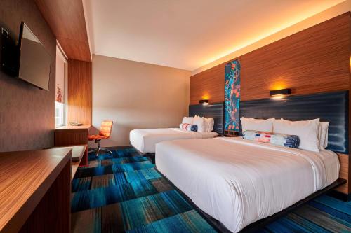 a hotel room with two beds and a flat screen tv at Aloft Cleveland Airport in North Olmsted