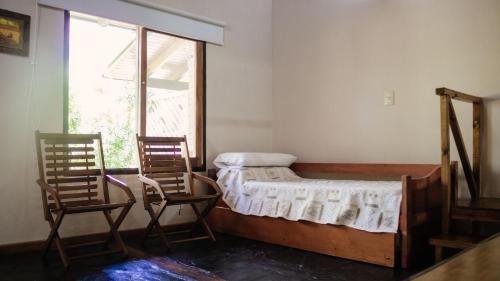 a bedroom with two chairs and a bed and a window at Complejo Paranay in Puerto Paranay