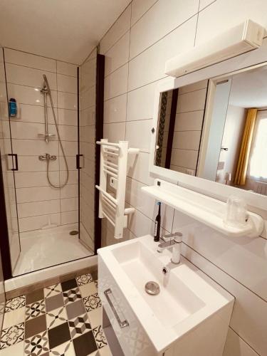 a white bathroom with a sink and a shower at Le Clos Robinson in Martin-Église