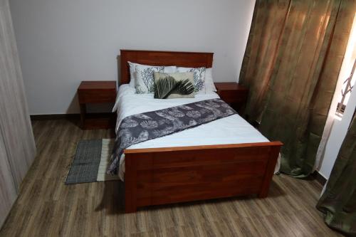 a bed with a wooden headboard in a room at Lolani Apartments in Lusaka