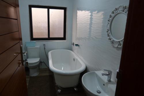 a bathroom with a sink and a toilet and a mirror at Lolani Apartments in Lusaka