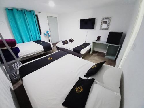 a bedroom with two beds and a desk with a television at RCH Suite in Mexico City