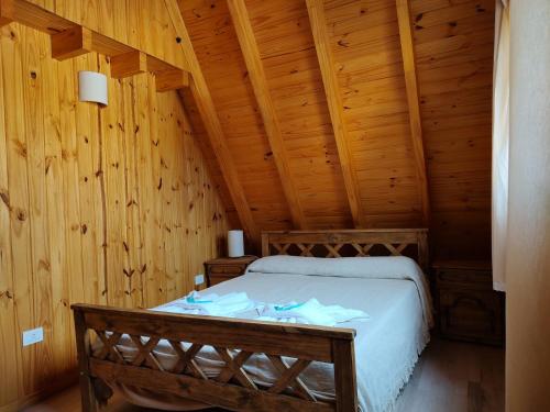 a bedroom with a bed in a wooden room at COMPLEJO AIKEN CURA in Junín de los Andes