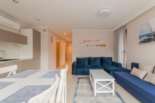Apartament Stegna Marine في ستيغنا: غرفة معيشة مع أريكة زرقاء وطاولة