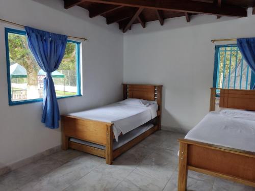 two beds in a room with two windows at Hosteria Puerta del Nus in Cisneros