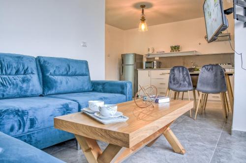uma sala de estar com um sofá azul e uma mesa de madeira em Galilee Hills - Resort & Suites em Maghār