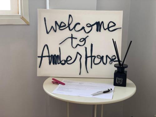 einen Tisch mit einem Schild, auf dem steht: Willkommen im Amistle House in der Unterkunft Amber House in Arinaga