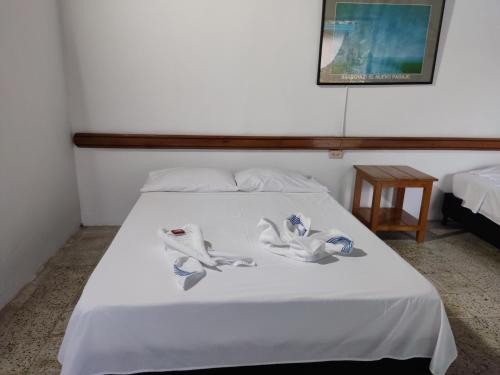 a bed with white sheets and shoes on it at Hosteria Puerta del Nus in Cisneros
