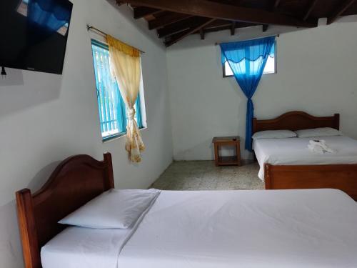 a bedroom with two beds and a tv and two windows at Hosteria Puerta del Nus in Cisneros