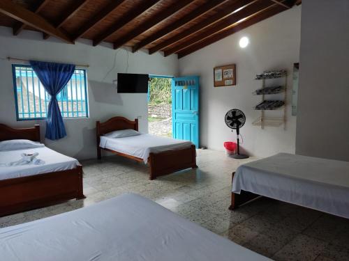 a bedroom with two beds and a blue door at Hosteria Puerta del Nus in Cisneros