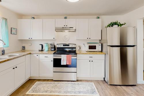a kitchen with white cabinets and a stainless steel refrigerator at Cedar Street Cottage in Eureka