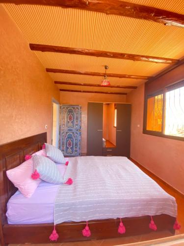 a bedroom with a large white bed with pink pillows at CENTRE D'ESTIVAGE IMi OUADDAR in Imi Ouaddar