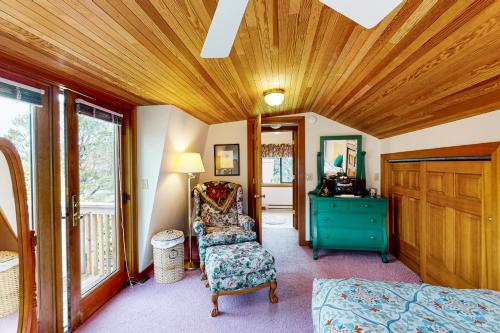 Cannon Beach Cottage في كانون بيتش: غرفة نوم بسقف خشبي وكرسي وخزانة