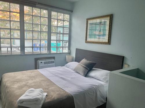 a bedroom with a bed with white sheets and windows at Casa Magdalena in San Juan