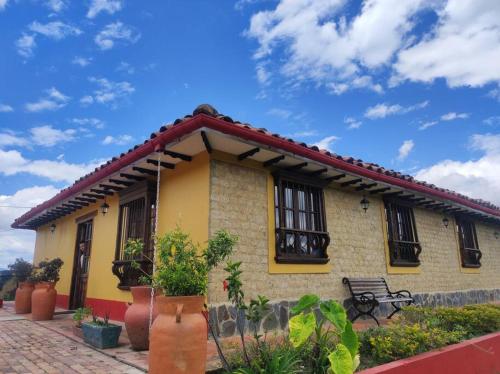 uma casa amarela com um banco à frente em Casa Finca El Mirador frente a la laguna de Fúquene em Fúquene