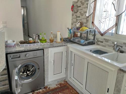 a kitchen with a washing machine and a sink at magnifique maison, bien équipé in Kelibia