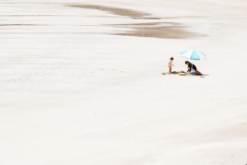 two people on the beach with an umbrella at Villa Yumigahama in Minamiizu