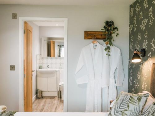 a white robe hanging on a door in a bathroom at Swallow Lodge - Uk42540 in Winforton