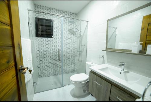 a bathroom with a shower and a toilet and a sink at VillaLunaCaridad in Jarabacoa